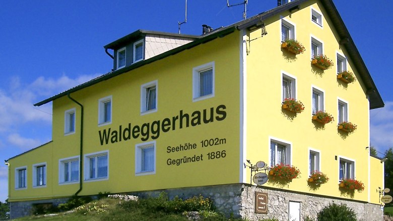 Waldeggerhaus, © Waldeggerhaus, Foto Susi Apfler Gelbes Gebäude mit der Aufschrift 'Waldeggerhaus', umgeben von Blumen.