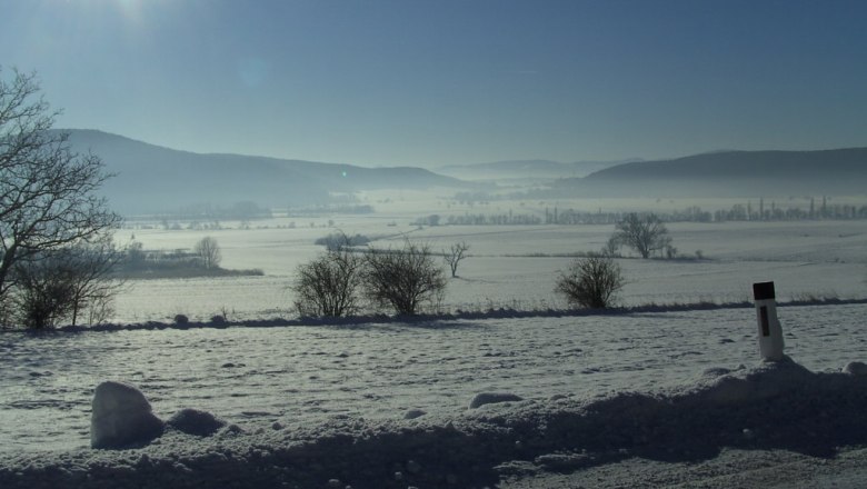 Landschaft in weiss, © Reep Winterliche Landschaft mit Schnee, Bäumen und Hügeln im Hintergrund, unter strahlender Sonne.