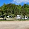 Stellplatz NP Zentrum, © Naturpark Hohe Wand Wohnmobile auf einem Stellplatz im Grünen mit Bäumen und Bänken.