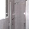 A modern shower cubicle with glass doors and chrome shower head in a tiled bathroom.