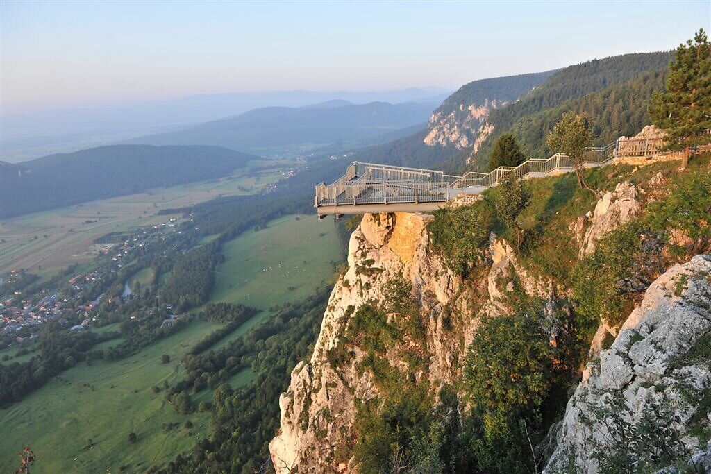 Ein atemberaubender Blick über die sanften Hügel und das weite Tal entfaltet sich von der schmalen Aussichtsplattform. Die frische Bergluft und das sanfte Licht der Abenddämmerung schaffen eine magische Atmosphäre, die zum Verweilen einlädt. Hier wird die Schönheit der Natur in ihrer reinsten Form erlebbar.