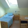 Ein kleines Einzelzimmer mit Bett, Schreibtisch und Dachfenster.