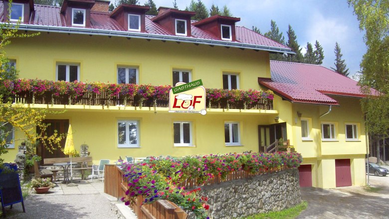 Yellow inn with red roofs and blooming flowers on the balcony.