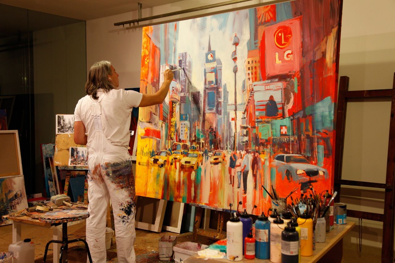 An artist paints a vivid cityscape on a large canvas in a studio.