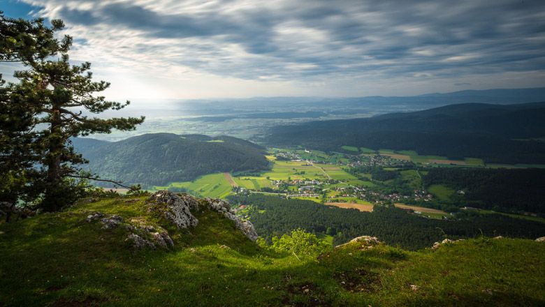 View from a cliff edge of a green landscape with hills and a village in the valley.