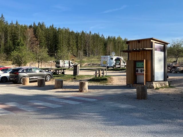 Parking lot at the Hohe Wand Nature Park Center with cars and campers, surrounded by forest.