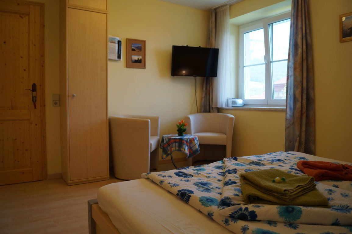 Comfort szoba ággyal, két fotel, asztal, TV és ablak.