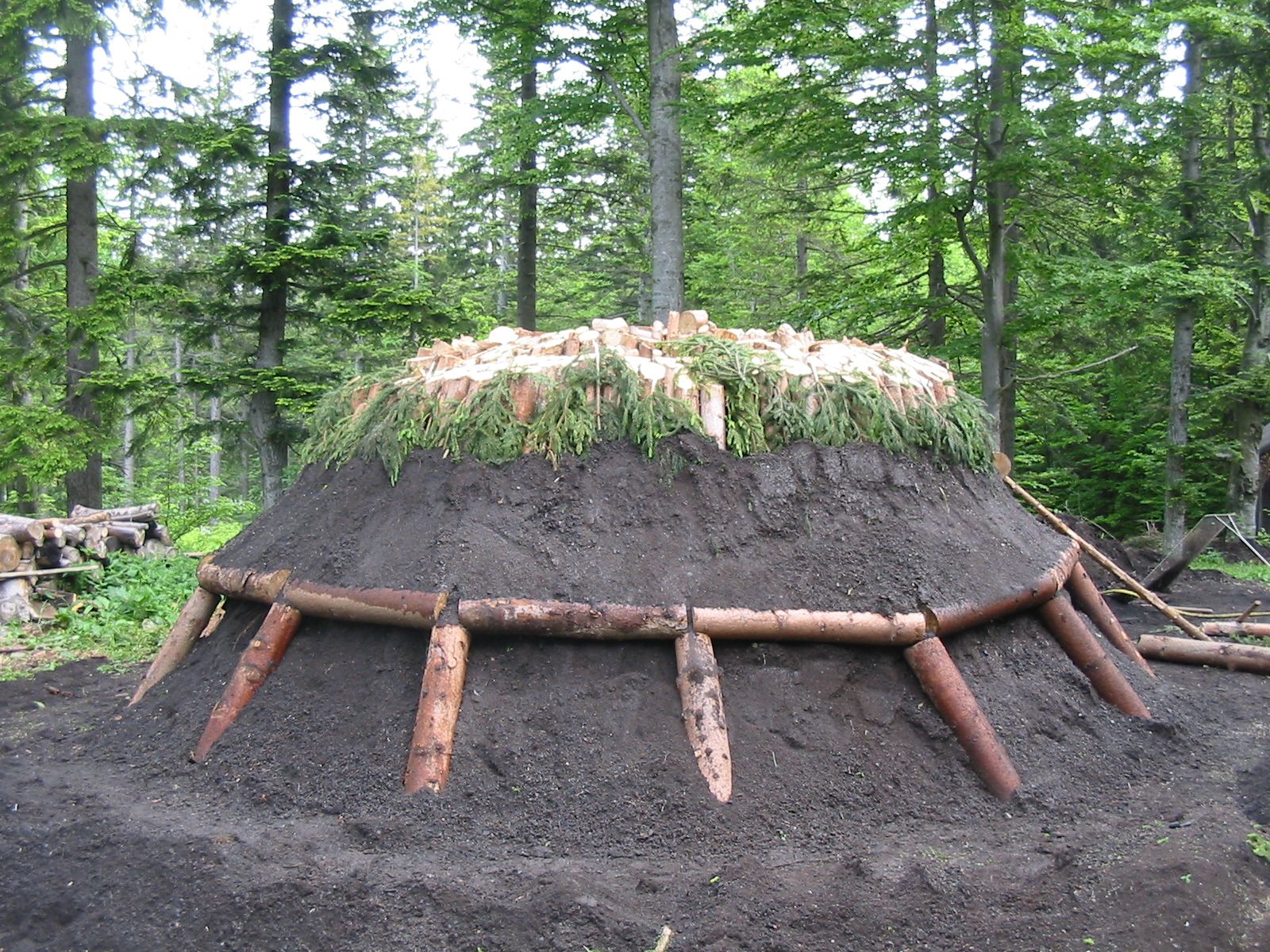 Holzkohle Rundmeiler, zur Hälfte mit Reisig und Erde bedeckt 