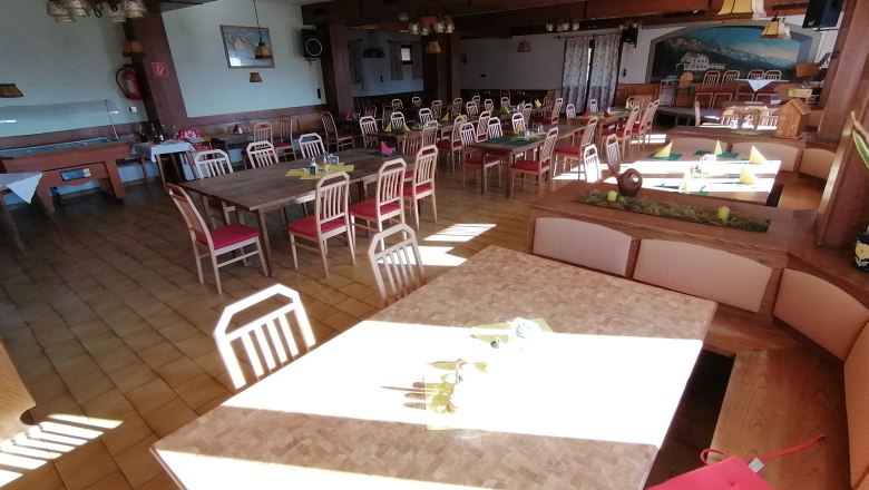 An empty dining room with wooden tables and red chairs at Gasthof Mohr.