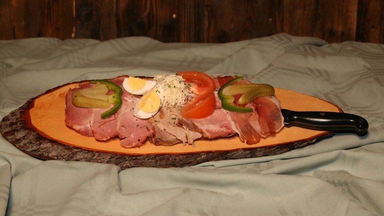 A rustic snack with cold cuts, egg, tomato and cucumber on a wooden board.
