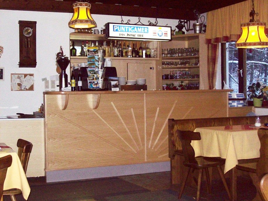 Innenansicht eines Gasthauses mit Theke und Tischen.