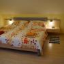 Gemütliches Schlafzimmer mit Doppelbett, bunter Blumenbettwäsche und Nachttischen mit Lampen.