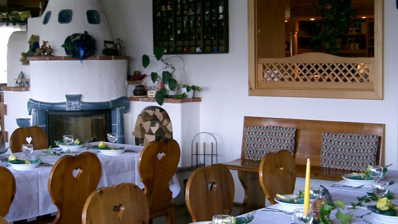 Cozy dining room with set tables, wooden furniture and tiled stove.