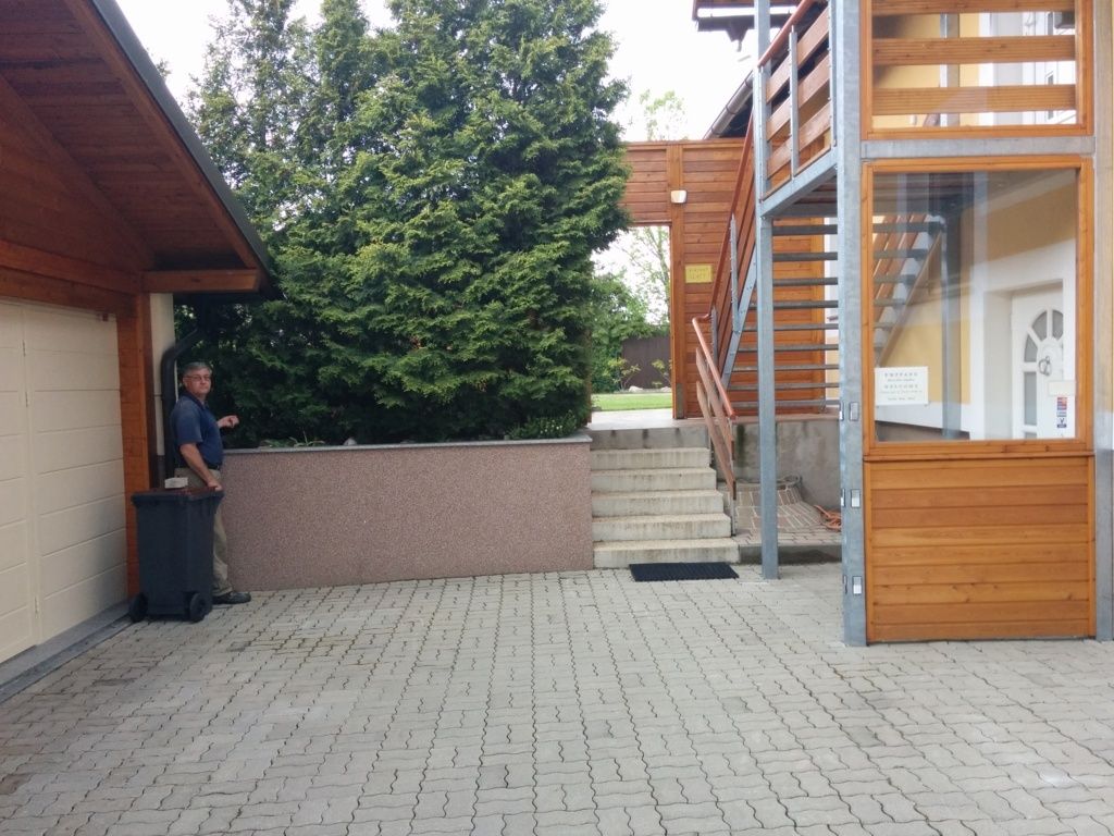 Udvar panorámalépcsővel és emberrel a szemetes mellett.