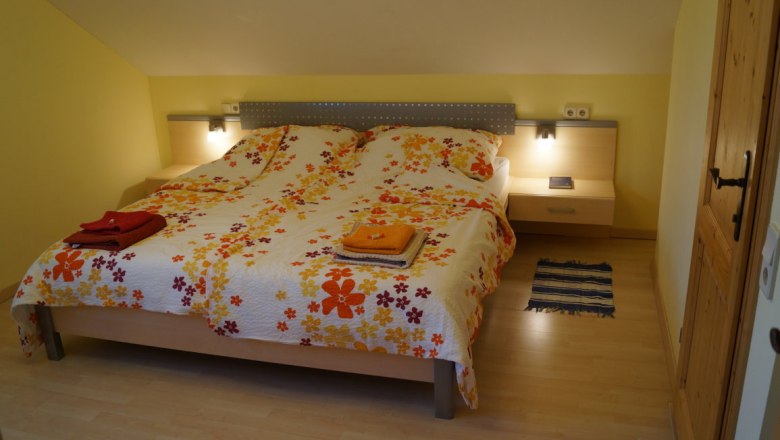 Comfortable bedroom with double bed, colorful floral bedding and bedside tables with lamps.
