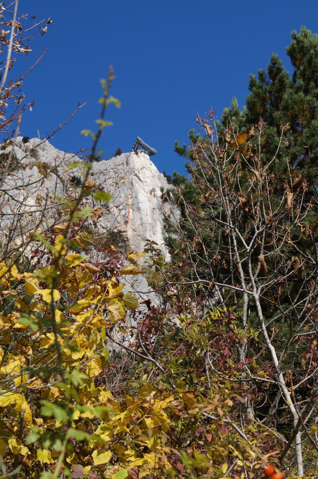 Sziklán lévő kilátó, őszi fákkal körülvéve.