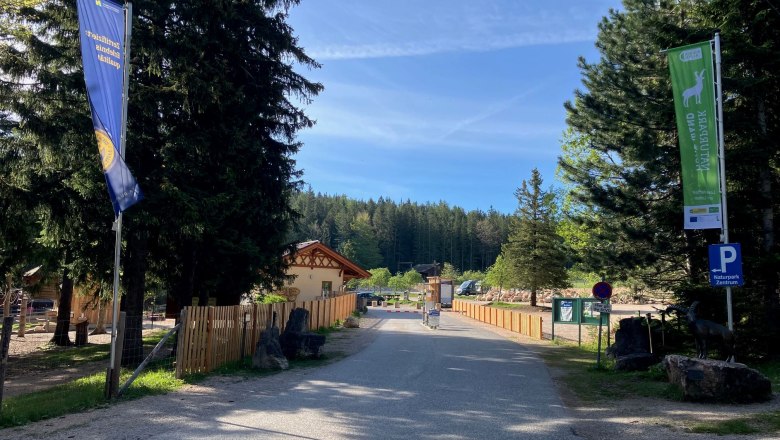 Einfahrt zum Naturpark Zentrum mit Fahnen und Bäumen.