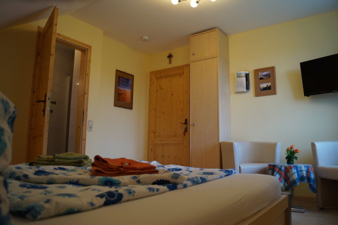 Hangulatos hotelszoba fabútorokkal, ággyal, TV-vel és ülősarokkal.