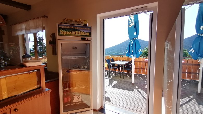 View from inside onto a terrace with parasols and mountains in the background.