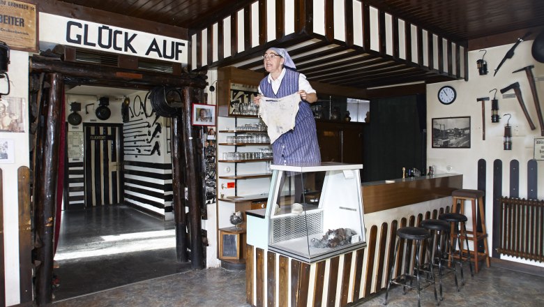 Interior view of a mining museum with a person in traditional clothing standing on a counter.