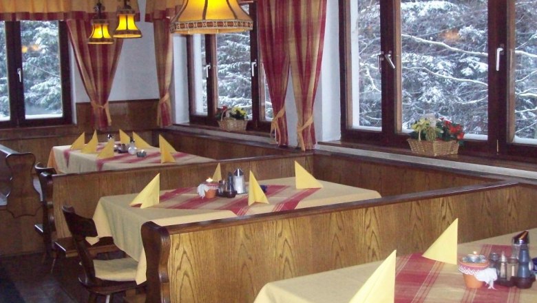 Interior view of a cozy inn with wooden furniture and laid tables.