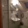 Ein Badezimmer mit Dusche, Waschbecken, Spiegel und Dachfenster.