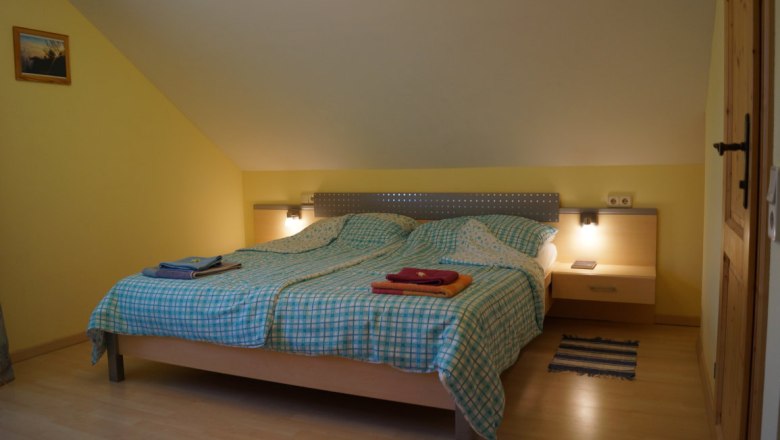 Schlafzimmer mit Doppelbett, karierten Bettdecken und Nachttischlampen.