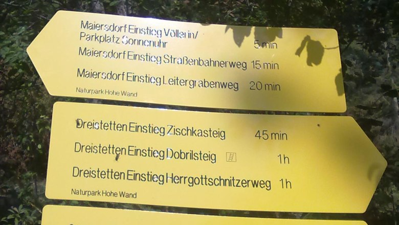 Gelbe Wegweiser im Naturpark Hohe Wand mit verschiedenen Wanderwegen und Gehzeiten.