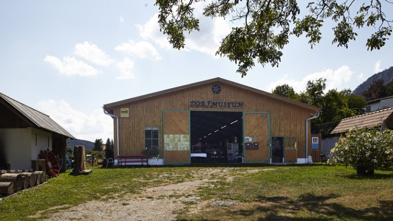 Exterior view of the Maiersdorf village museum with wooden houses and trees.