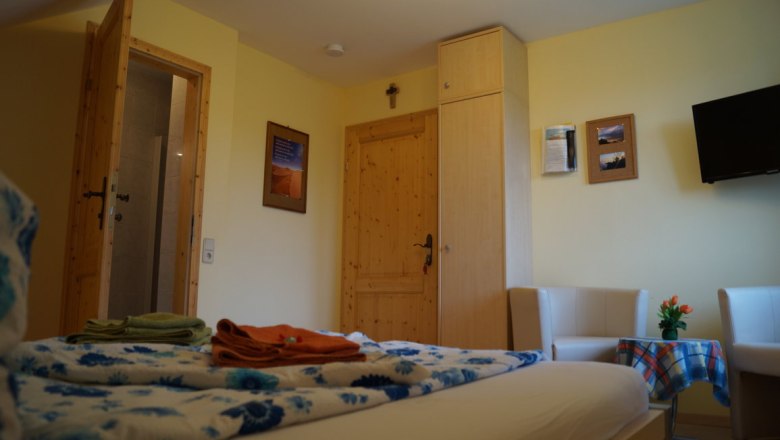 Komfortables Hotelzimmer mit Holzmöbeln, Bett, TV und Sitzbereich.