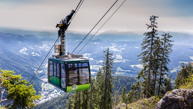 Seilbahn in den Bergen mit Blick auf bewaldete H&auml;nge und T&auml;ler.