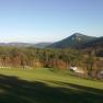 Landscape with hills, forest and meadows under a clear sky.