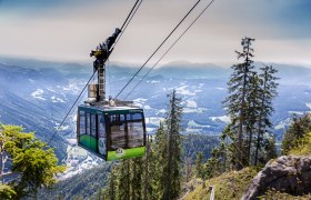 Seilbahn in den Bergen mit Blick auf bewaldete Hänge und Täler.